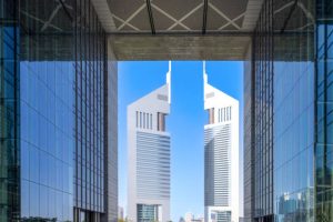 Modern twin skyscrapers of commercial real estate in a bustling city, framed by glass buildings.