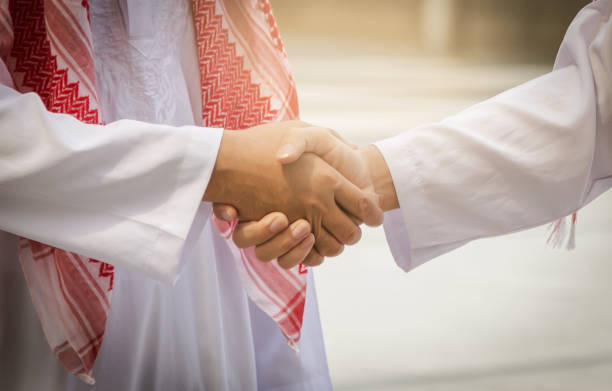 Two people in traditional attire shaking hands, symbolizing a real estate investment deal in Dubai.